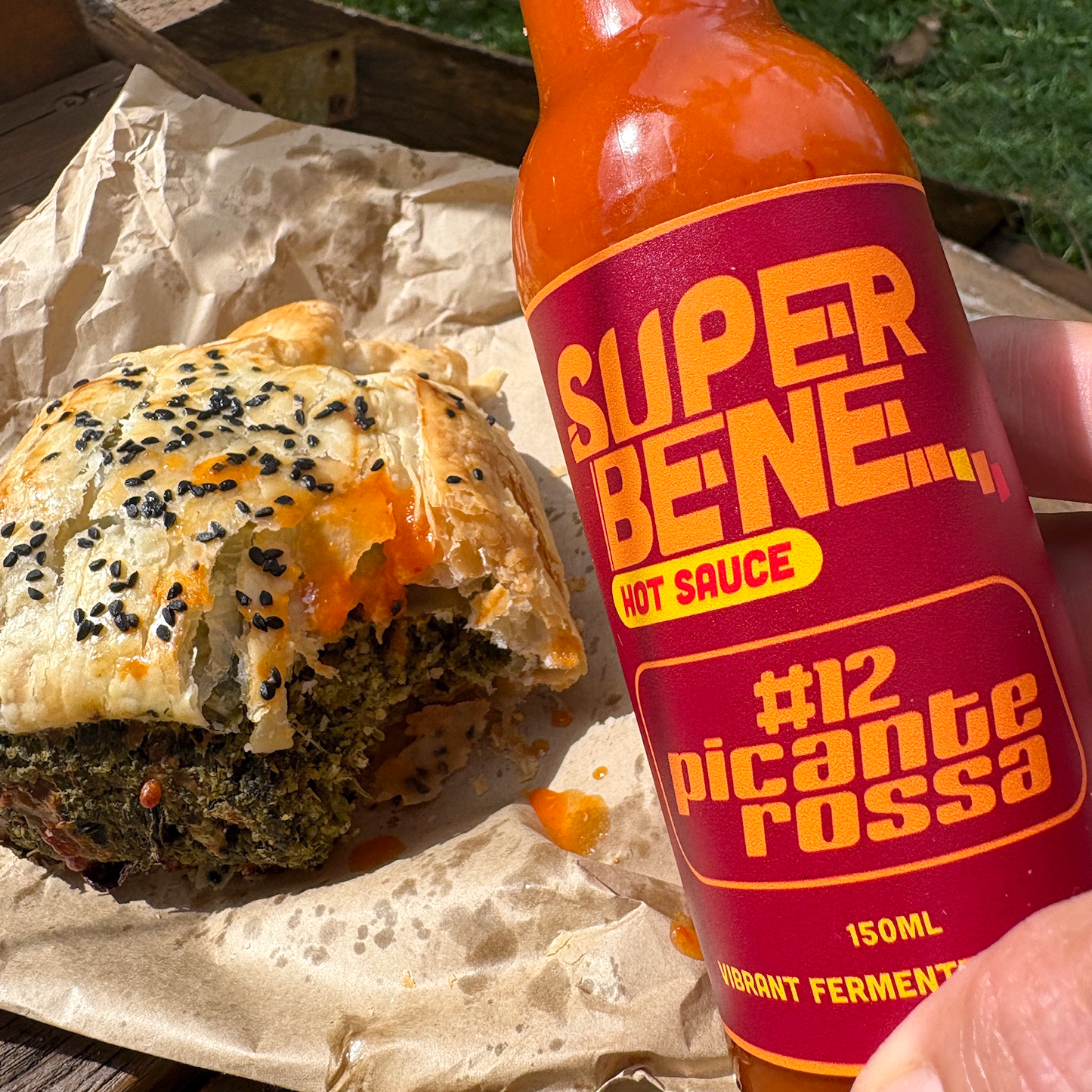 Super Bene hot sauce bottle with a pastry on a wooden surface